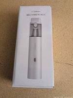 Front of sealed retail box showing product image of slim cylindrical vacuum and branding