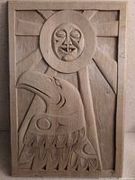 Full view of carved wood panel showing sun face and eagle design