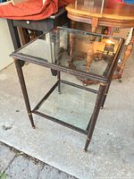 Square metal side table with glass top and shelf, angled view