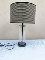 Full view of table lamp with glass base and striped drum shade