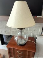 Full view of lamp showing glass globe base and cream shade