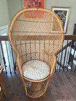Front view of natural tan wicker peacock chair showing full fan back and cushion