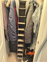 Full length view of tan fabric organizer hanging between jackets showing all cubbies