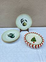 Stack of pear plates, one displayed on stand, stack of Christmas plates front