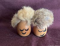 Front view of both wood figures showing painted faces and fur hair