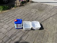 Reliance Aqua-Pak water jug and two white wash tubs placed on pavement