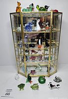 Full view of brass and glass curio cabinet with figurines inside and additional figurines placed in front