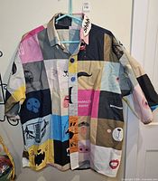 Front view of multicolor graphic button-up shirt on hanger