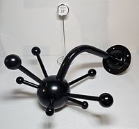Side angled view of complete coat rack showing arms, sphere, support arm and mounting flange