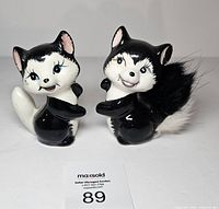 Front view of both ceramic skunk figurines