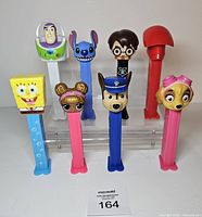Front view of all eight Pez dispensers standing on clear riser