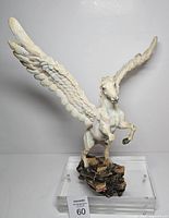 Front view of ivory resin Pegasus figurine with wings spread on rocky base