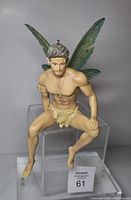 Front three-quarter view of seated resin pixie showing torso, wings, gold clothing and jewelry