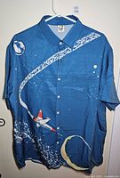 Front view of blue button-up shirt displaying rocket and space graphics