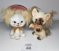 Front view showing both ceramic cat figurines, their faux fur manes, bows, and overall condition
