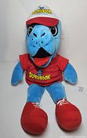 Full view of blue Slippery the Seal puppet wearing red shirt, red sneakers and white cap