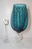 Front view of teal ribbed vase beside lot number stand