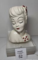 Front view of white ceramic lady head planter with red accents