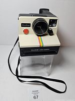 Front view of Polaroid OneStep Land Camera showing lens, shutter button, rainbow stripe