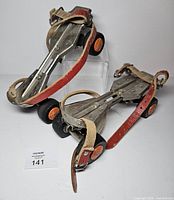 Pair of adjustable metal strap-on skates standing upright