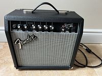 Front view showing Fender logo, control panel, grille, attached cord