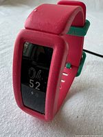 Front view of pink Fitbit kids tracker powered on