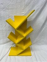 front view of yellow zigzag shelf showing five angled tiers and base
