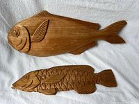 Both wooden fish plaques side by side on white cloth