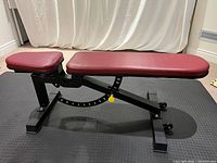 Side view of bench flat position showing red cushions and black frame