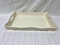 Top view of off-white wooden tray with scalloped edges and cutout handles