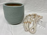 Planter and bundled macramé hanger with hook on white background