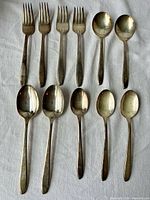 Full set of 11 silverplate flatware pieces laid out on cloth