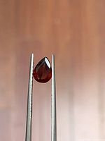 Pear cut red garnet held by tweezers
