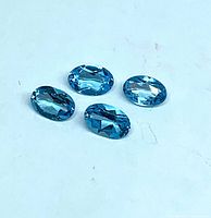 Four oval faceted blue topaz stones grouped together