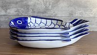 Side stack view of four blue and white ceramic fish platters