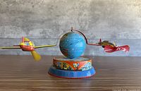 Front angle of tin litho toy showing globe and two airplanes