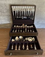 Open chest displaying knives in lid and flatware in upper drawer
