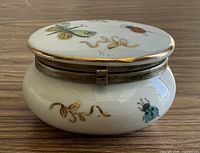 Closed trinket box side view showing decoration and metal rim