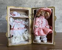 Trunk interior showing doll, spare dress, hat, necklace