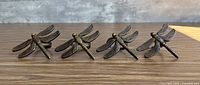 Four dragonfly napkin rings arranged in a line displaying top view of wings and bodies