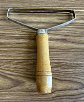 Full view of lint remover showing wood handle and metal frame