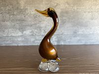 Front angled view of amber Murano glass duck figurine on clear glass base