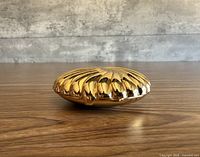 Closed gold shell votive holder side view