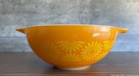 Side view of orange bowl with yellow daisy pattern visible