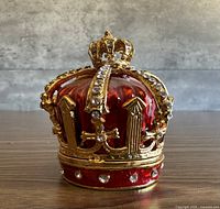 Front view of red enamel crown trinket box showing gold detailing and rhinestones