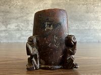 Front view showing cylindrical holder and two monkey figures
