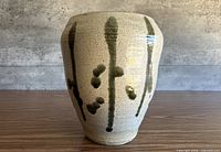Front view of speckled stoneware vase with green brush motif