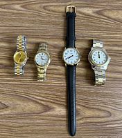 Group shot of four wristwatches on wooden surface
