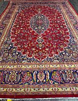 Full view of red field Persian rug with medallion and borders