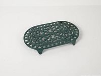 Top view of green enameled oval cast iron trivet showing openwork pattern